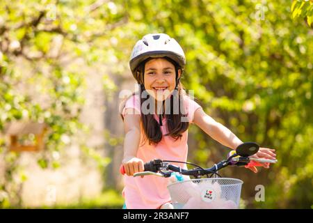 Une fille souriante en casque sur le vélo de la ceinture rose Banque D'Images