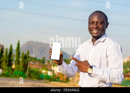 copie de l'image spatiale d'un homme africain excité tenant et pointant vers un smartphone avec écran blanc vierge. espace de copie, écrire pour la publicité Banque D'Images