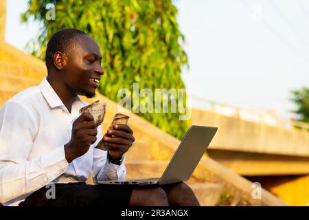 Bon homme d'affaires assis avec son ordinateur portable et comptant beaucoup d'argent. jour de paie de la transaction commerciale réussie Banque D'Images