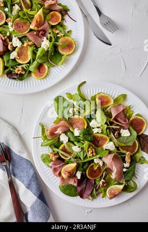 Salade avec figues fraîches, prosciutto, fromage de chèvre et noix Banque D'Images