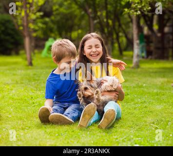 Les enfants jouent avec un petit chien dans l'arrière-cour Banque D'Images