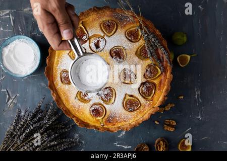 Saupoudrer la poudre de sucre sur une tarte aux figues au mascarpone fraîchement cuite Banque D'Images