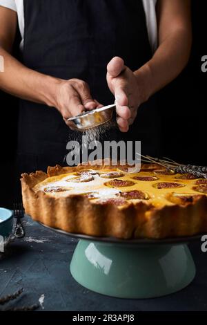 Saupoudrer la poudre de sucre sur une tarte aux figues au mascarpone fraîchement cuite Banque D'Images