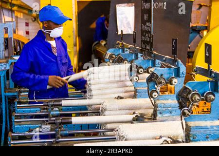 Travailleur d'usine africain sur un métier à tisser de ligne de montage de trame de cobobineuse Banque D'Images