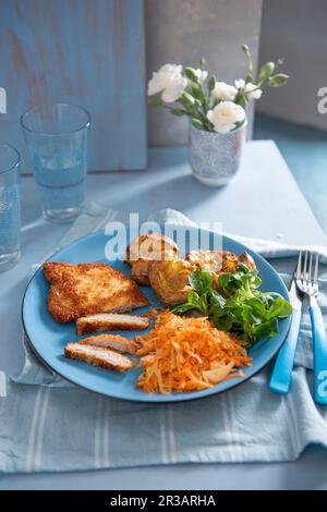 Schnitzel de porc avec pommes de terre écrasées, choucroute, carottes et salade de laitue agneaux Banque D'Images