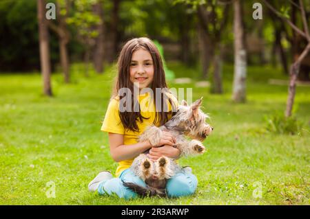 Fille qui se repose dans la cour avec un petit chien Banque D'Images