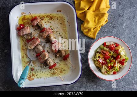 Brochettes à l'extrémité chiche au bachon, champignons et poivron rouge, salade de laitue, tomates, poivrons, concombre Banque D'Images