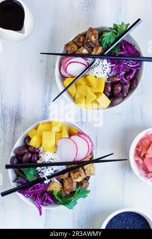 Bol à poke végétalien avec riz basmati, mangue, tofu frit, chou violet, radis, olives, gingembre mariné et sésame noir Banque D'Images