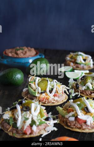 Tostadas de poulet aux poivrons jalapeno, olives noires, crème aigre, laitue, poulet râpé et coriandre fraîche Banque D'Images