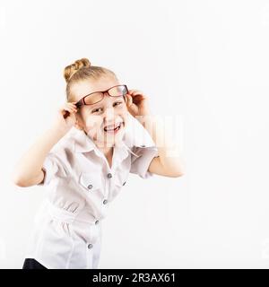 Drôle petite fille portant des lunettes imite un enseignant strict contre fond blanc. Petit stu Banque D'Images