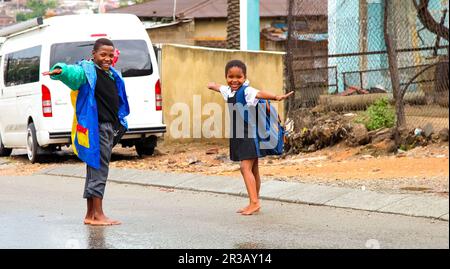 Des écoliers africains jouant sur une route principale dans le canton d'Alexandra, un établissement formel et informel Banque D'Images