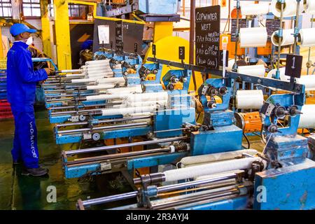 Travailleur d'usine africain sur un métier à tisser de ligne de montage de trame de cobobineuse Banque D'Images