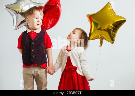 Enfants portant des ballons en forme d'étoile. Des enfants heureux jouant avec des ballons colorés en papier d'aluminium brillant ag Banque D'Images