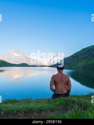 Un homme assis au lac Bachalpsee, Un homme regardant le lac, réflexion du lac Bachalpsee en Suisse. Style de vie en extérieur. Bannière panoramique de Banque D'Images