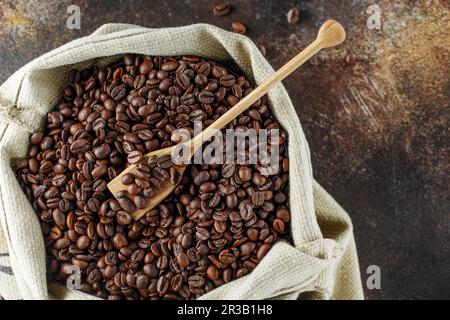 Grains de café noirs en studio. Grains de café fraîchement torréfiés dans un pot en verre. Banque D'Images