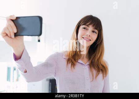 Femme souriante prenant le selfie par smartphone Banque D'Images