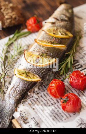 Bar de mer cuit au four avec citron et herbes. Poisson de mer, cuit entièrement Banque D'Images