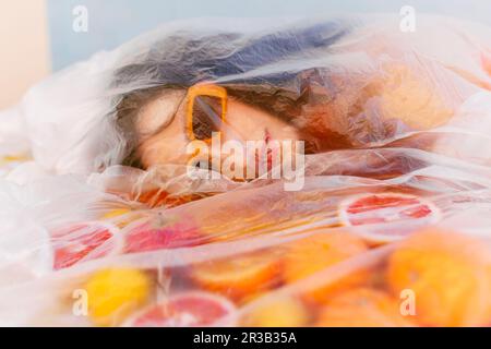 Femme portant des lunettes de soleil aux agrumes recouvertes d'un film plastique Banque D'Images