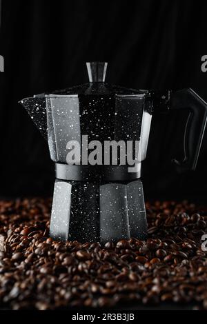 Grains de café noirs en studio. Cafetière geyser sur fond de grains de café fraîchement torréfiés Banque D'Images