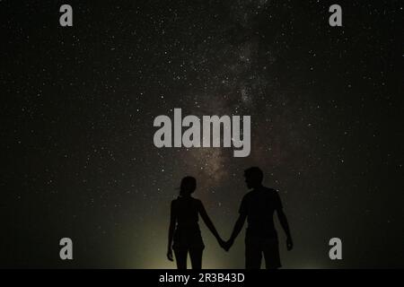 Silhouette de couple tenant les mains debout la nuit Banque D'Images