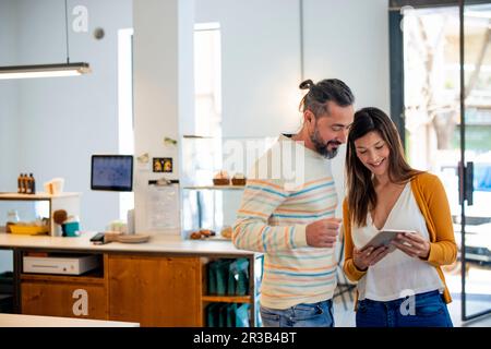 Homme regardant un Tablet PC tenu par le propriétaire dans un café Banque D'Images