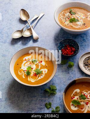 Soupe de carottes au lait de coco, piments rouges, coriandre, graines de sésame blanc et de blach Banque D'Images