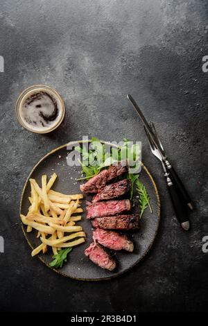 Steak de t-bone grillé avec roquette et frites Banque D'Images