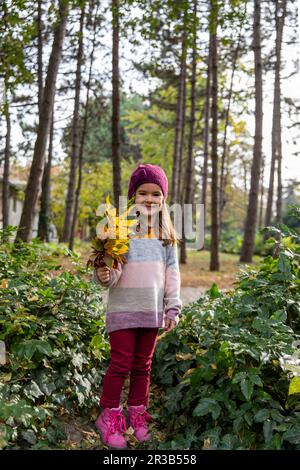 Fille souriante tenant un bouquet de feuilles Banque D'Images