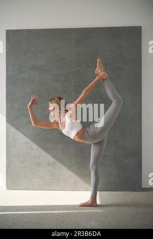 Femme pratiquant la posture debout de l'arc Banque D'Images