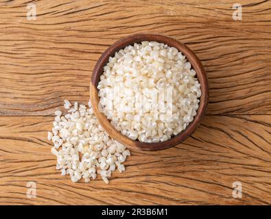 Canjica séché, maïs hominy ou blanc sur un bol sur une table en bois. Banque D'Images