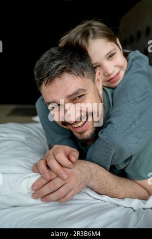 Le père passe du temps libre avec son fils au lit Banque D'Images