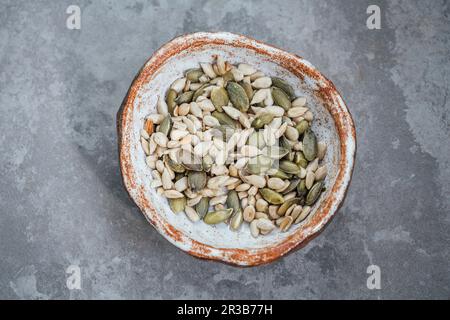 Graines de potiron et de tournesol grillées dans un bol fait à la main Banque D'Images