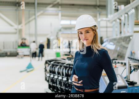 Femme d'affaires portant un casque de sécurité en usine Banque D'Images