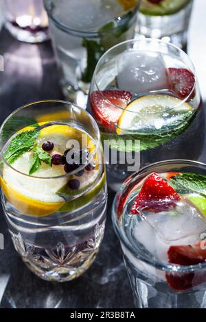 Divers verres d'eau remplis de fruits, de menthe et de gingembre Banque D'Images