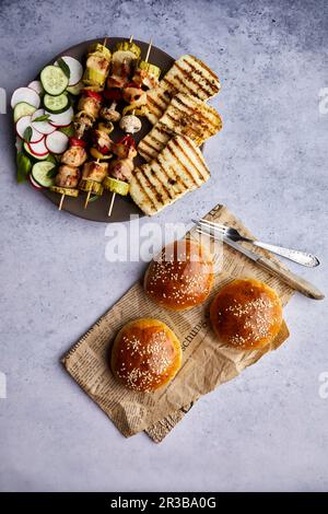 Brochettes de poulet au fromage halloumi grillé et salade fraîche servies avec des petits pains faits maison Banque D'Images