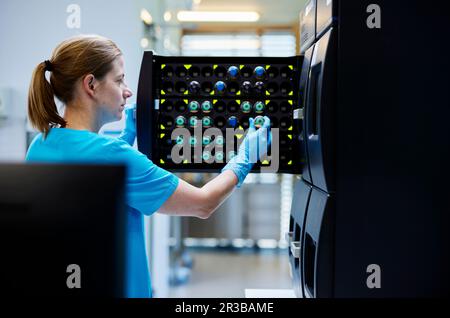 Un scientifique prend un flacon de produit chimique du compartiment de stockage dans un laboratoire microbiologique Banque D'Images