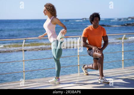 Couple faisant des exercices d'étirement sur la jetée dans la zone côtière Banque D'Images