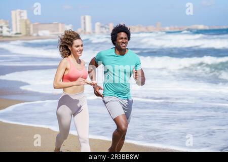 Heureux couple portant des vêtements de sport en course sur la mer Banque D'Images