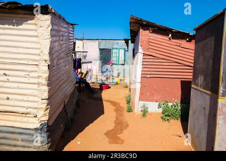 La mère et l'enfant africains lavant des vêtements dans le quartier de Soweto à faible revenu Banque D'Images