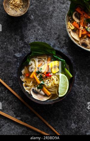 Soupe de nouilles aux carottes, champignons, pak choi et graines de sésame (Asie) Banque D'Images