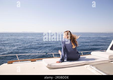 Femme assise sur la terrasse du bateau par beau temps Banque D'Images