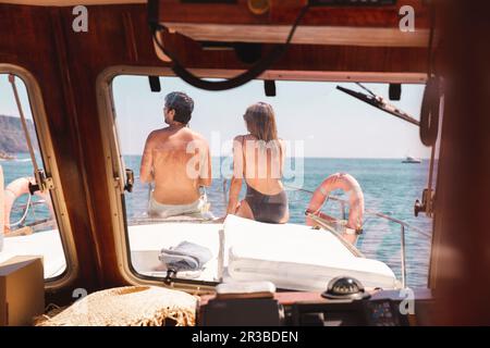 Homme et femme assis sur l'arc du navire vu par le pare-brise Banque D'Images