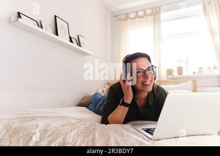 Indépendant attentionné avec ordinateur portable allongé sur le lit à la maison Banque D'Images