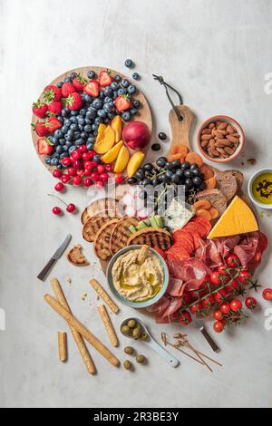 Assiette de charcuterie avec jambon, fromage, houmous, olives, fruits frais et pain Banque D'Images