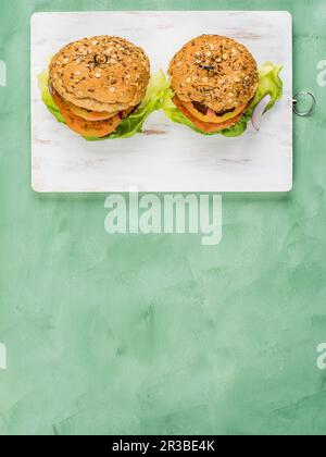 Hamburger végétalien composé d'un pain épeautre et d'une patty de soja et de légumes avec salade de laitue, tomate et oignon rouge Banque D'Images