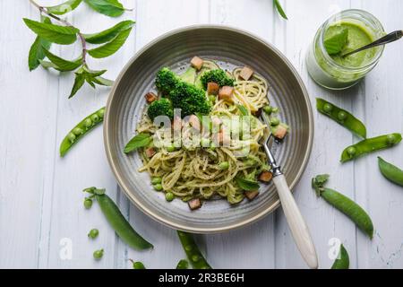 Spaghetti au pesto aux pois et à la menthe, brocoli et tofu fumé Banque D'Images