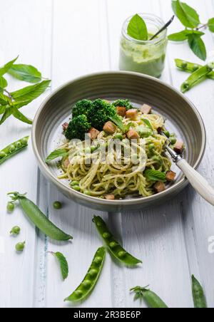 Spaghetti au pesto aux pois et à la menthe, brocoli et tofu fumé Banque D'Images