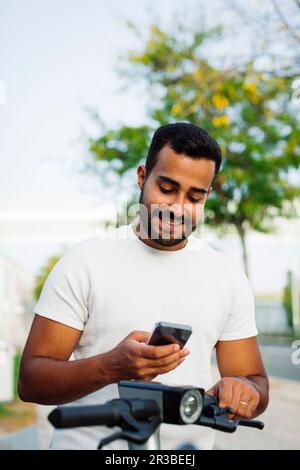 Homme utilisant un smartphone sur un scooter électrique Banque D'Images
