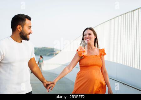 Femme enceinte heureuse tenant la main de l'homme sur la marche Banque D'Images