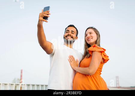 Homme souriant prenant le selfie avec une femme enceinte Banque D'Images